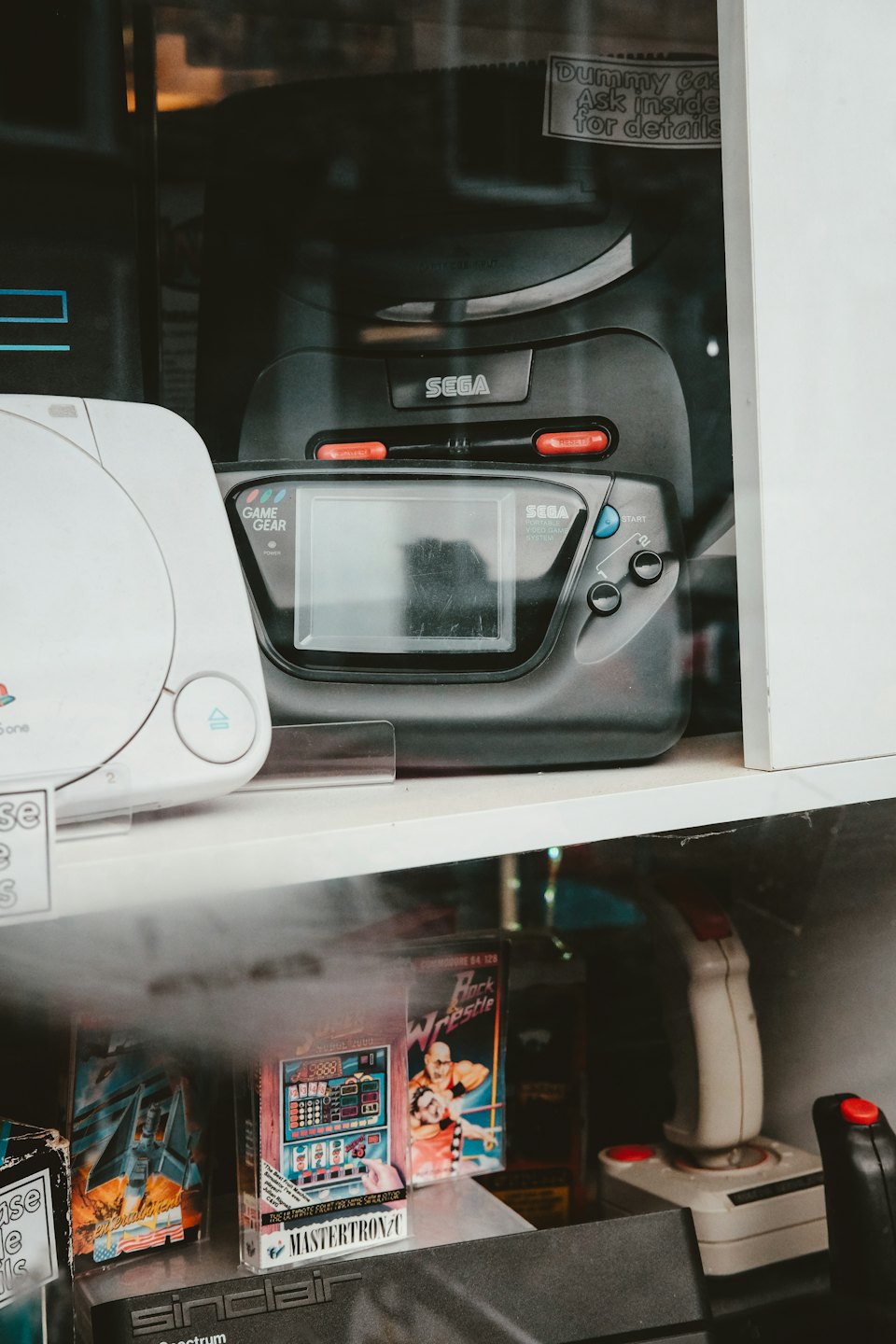 Console e accessori per videogiochi vintage esposti su scaffali.