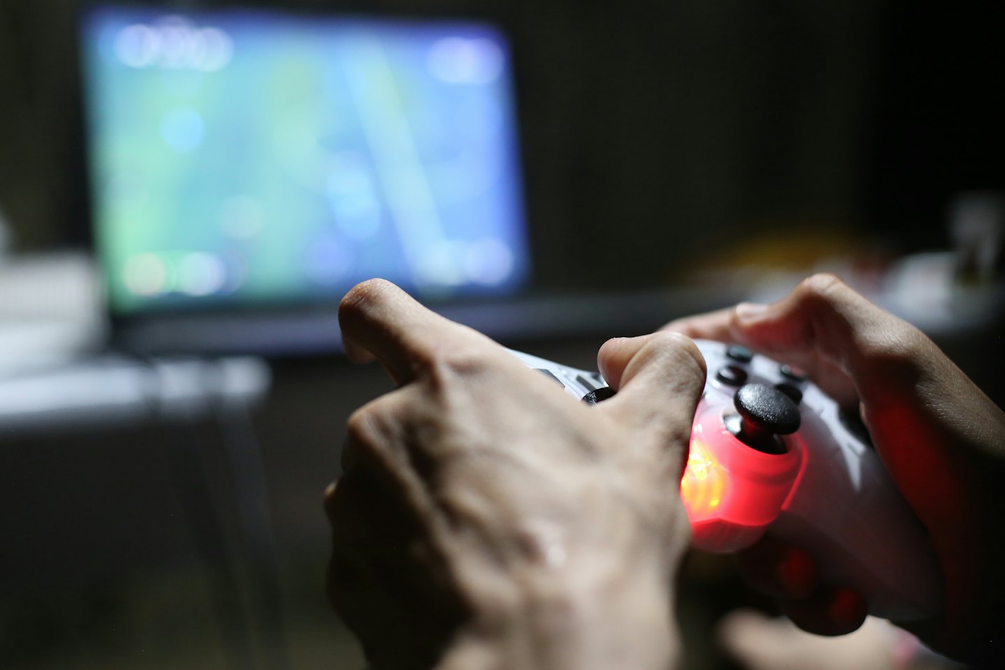 Mani che tengono un controller per videogiochi con una luce rossa brillante.