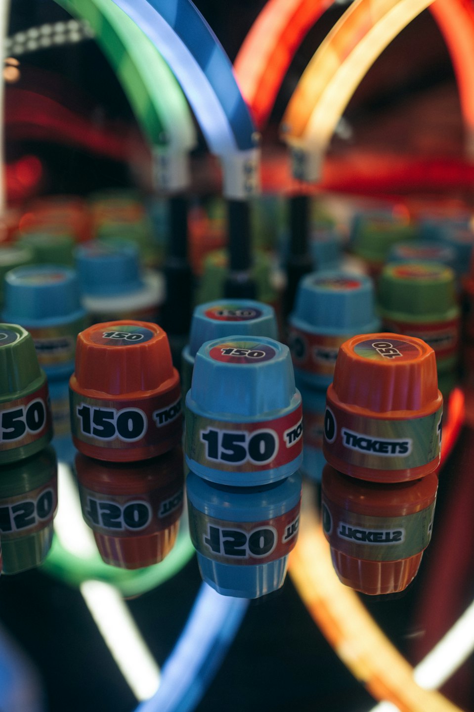 Gettoni colorati per giochi arcade che riposano su una superficie riflettente.